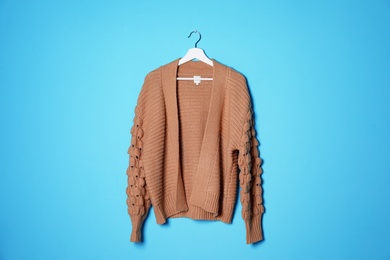 Hanger with stylish sweater on color background