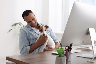 Young man with Jack Russell Terrier at desk in home office