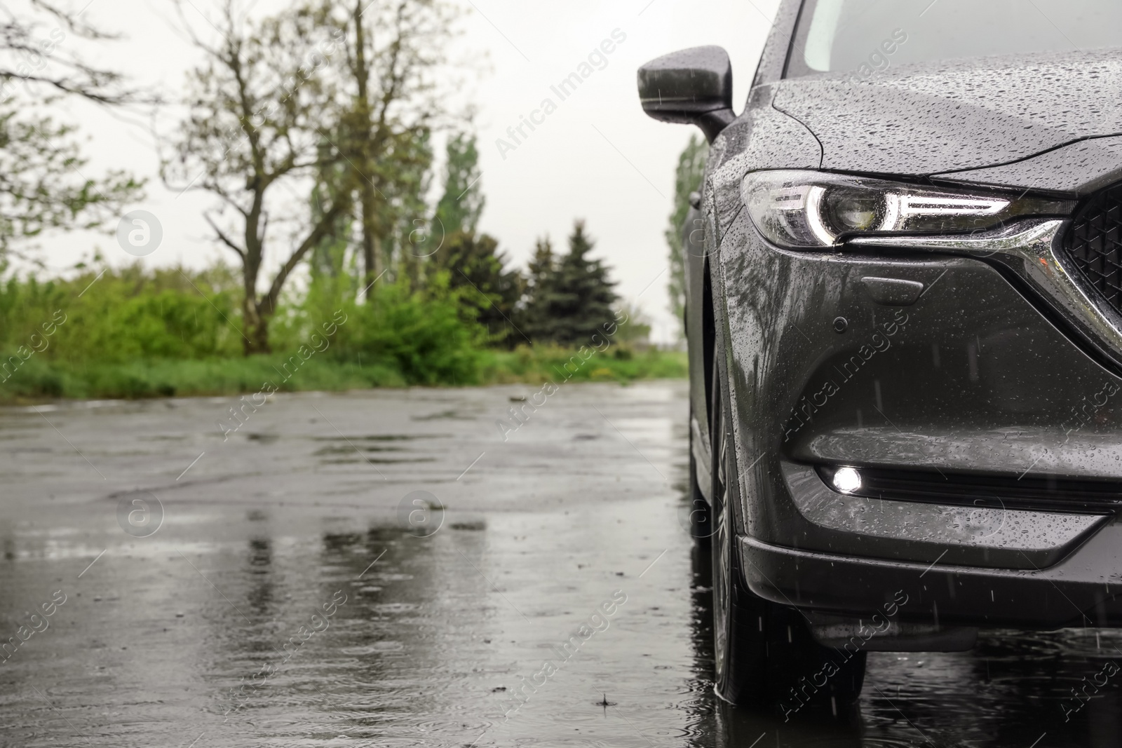 Photo of Modern car parked outdoors on rainy day