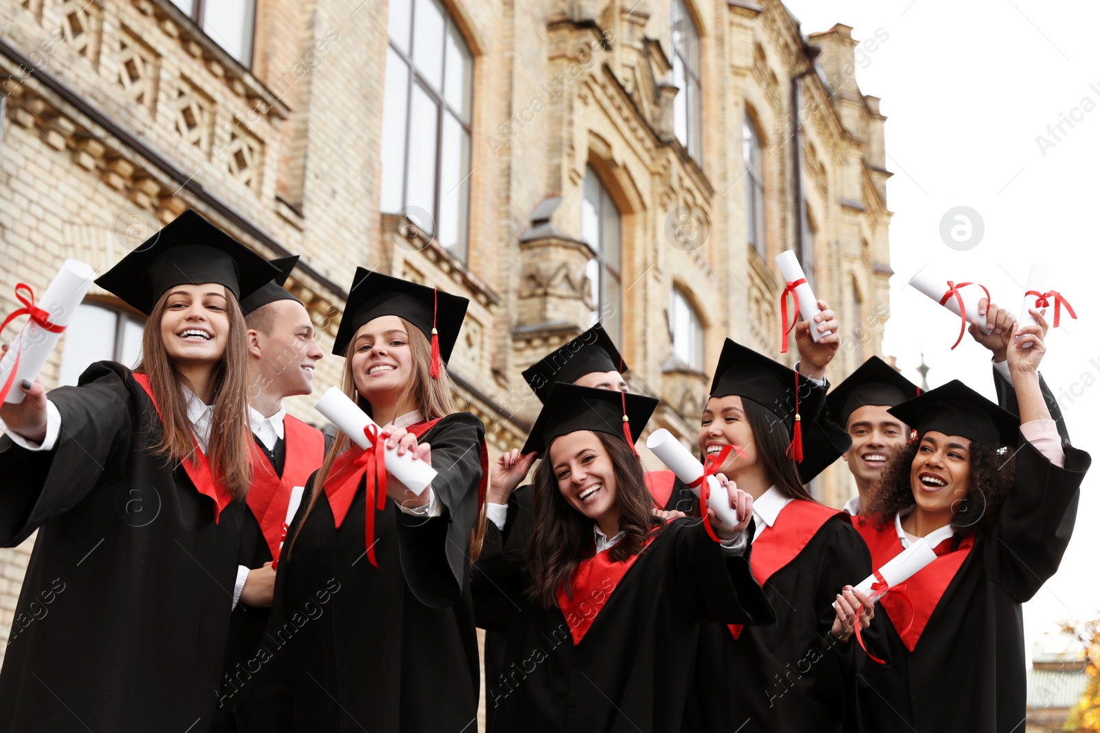 Photo of Happy students with diplomas outdoors. Graduation ceremony