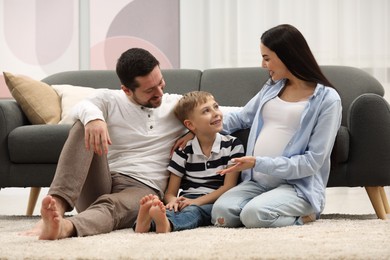 Photo of Pregnant woman spending time with her son and husband at home. Happy family