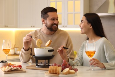 Photo of Affectionate couple enjoying fondue during romantic date in kitchen