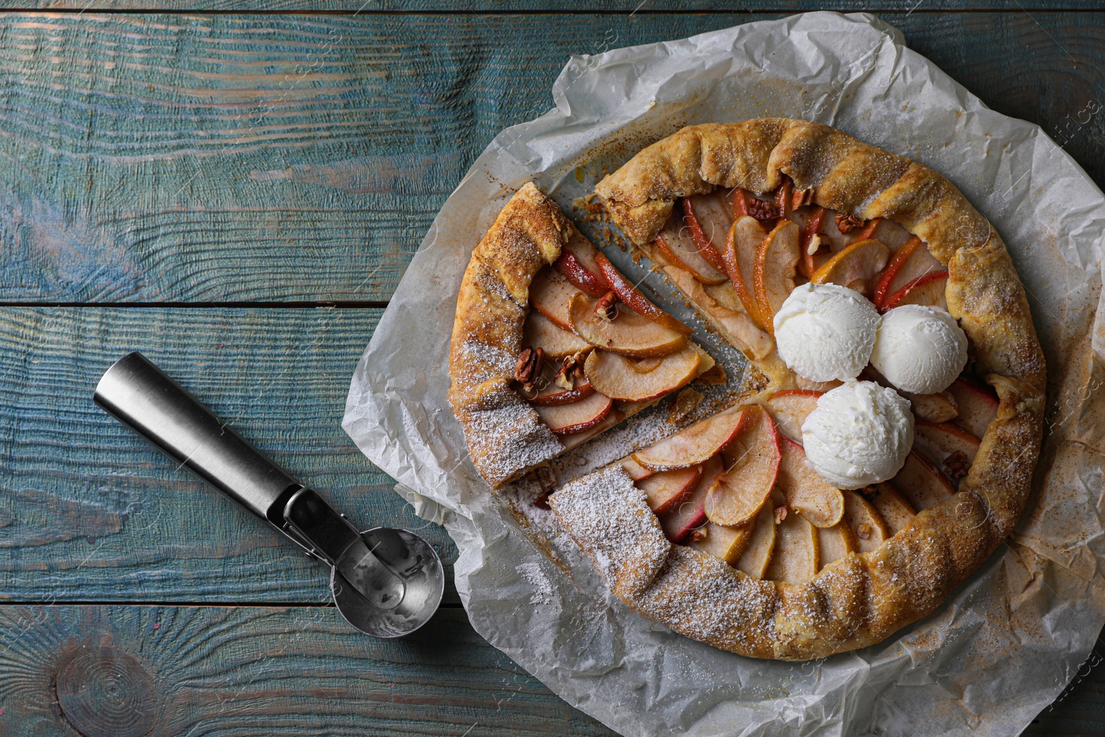 Photo of Delicious apple galette with ice cream and pecans on wooden table, flat lay