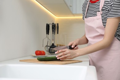 Photo of Young woman cutting finger with knife while cooking in kitchen, closeup