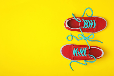 Photo of Shoes tied together on yellow background, flat lay with space for text. April Fool's Day