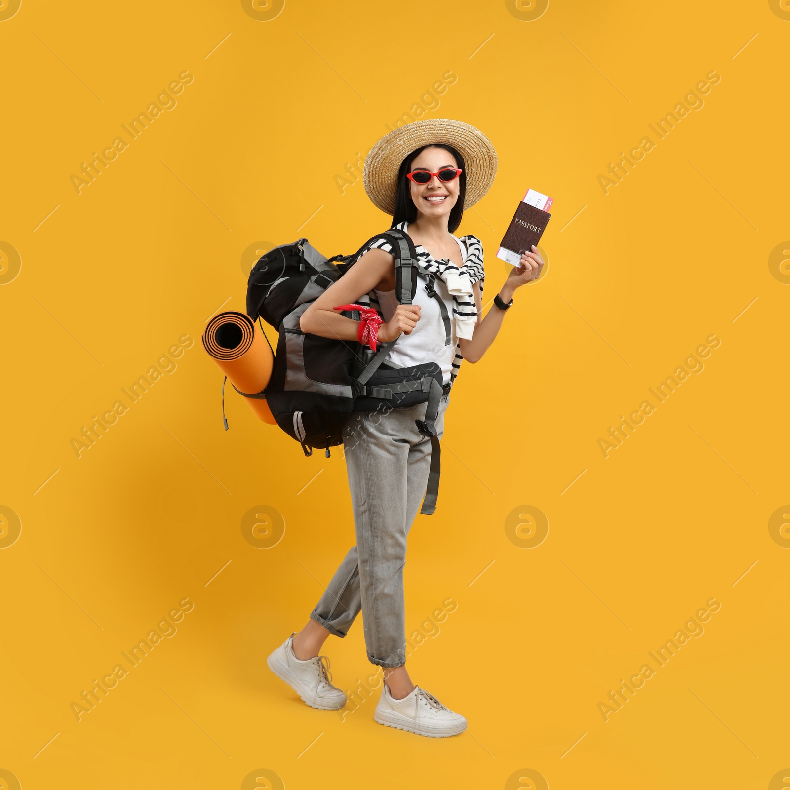 Photo of Happy female tourist with passport, ticket and backpack on yellow background