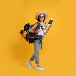 Happy female tourist with passport, ticket and backpack on yellow background