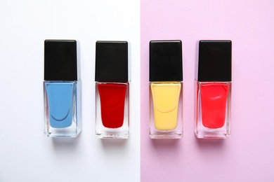 Photo of Bottles of nail polish on color background, top view