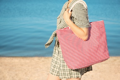 Photo of Woman holding bag on beach. Summer vacation