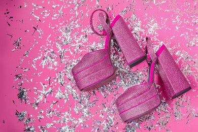 Photo of Fashionable punk square toe ankle strap pumps and confetti on pink background, flat lay with space for text. Shiny party platform high heeled shoes