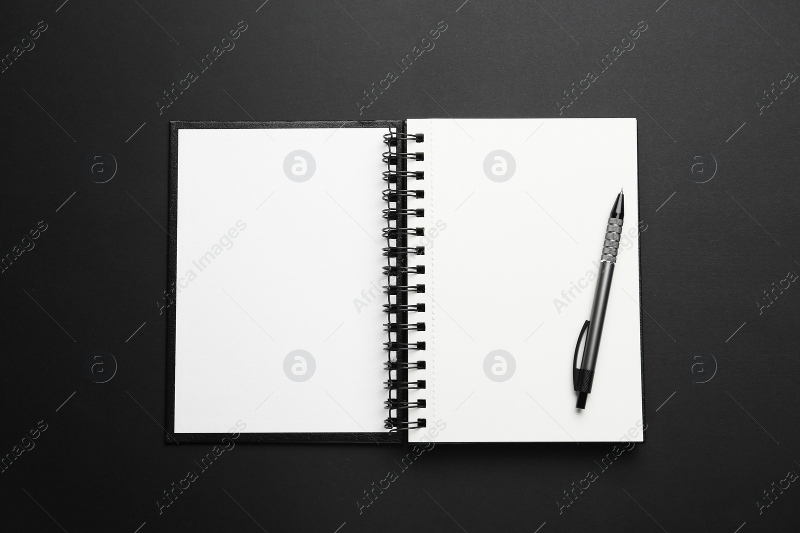 Photo of Notebook and pen on black background, top view