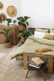 Comfortable bed and beautiful green houseplants in bedroom