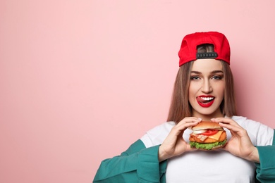 Pretty woman with tasty burger on color background. Space for text