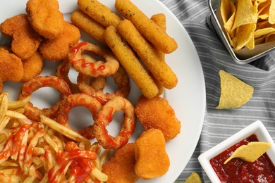 Photo of Different delicious fast food served with ketchup on napkin, flat lay