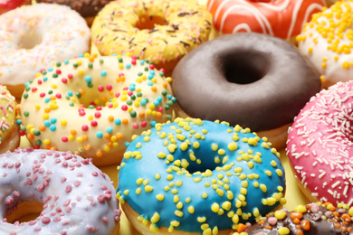 Photo of Delicious glazed donuts on yellow background, closeup