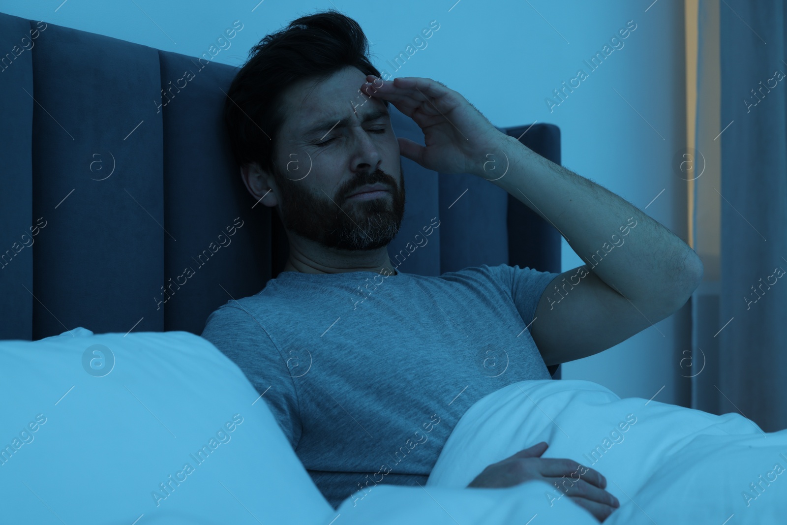 Photo of Man suffering from headache in bed at night