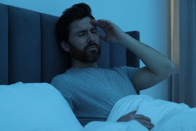 Man suffering from headache in bed at night