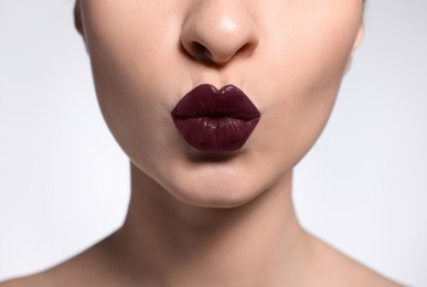 Photo of Young woman with beautiful lips makeup on light background, closeup