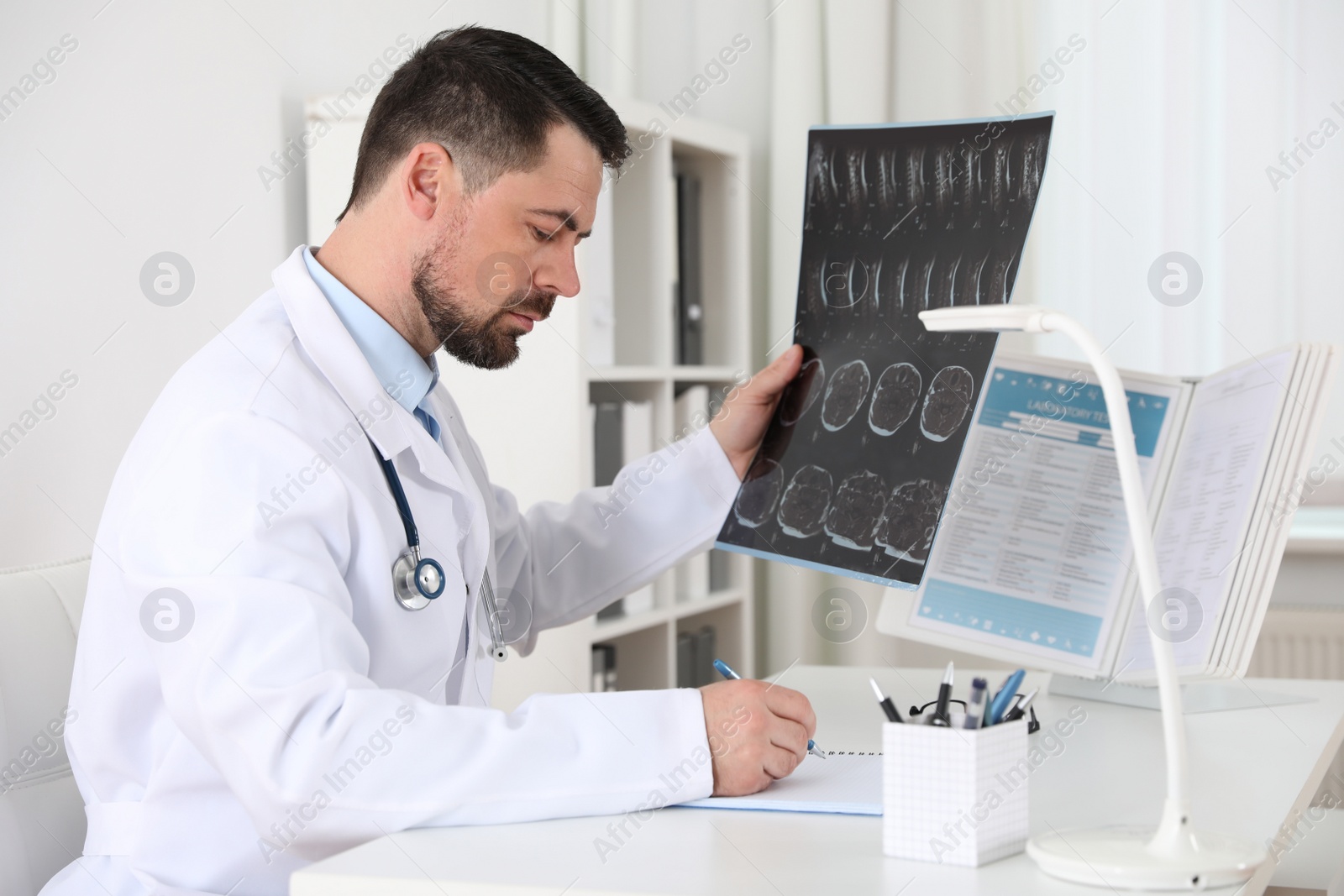 Photo of Orthopedist examining X-ray picture at desk in clinic