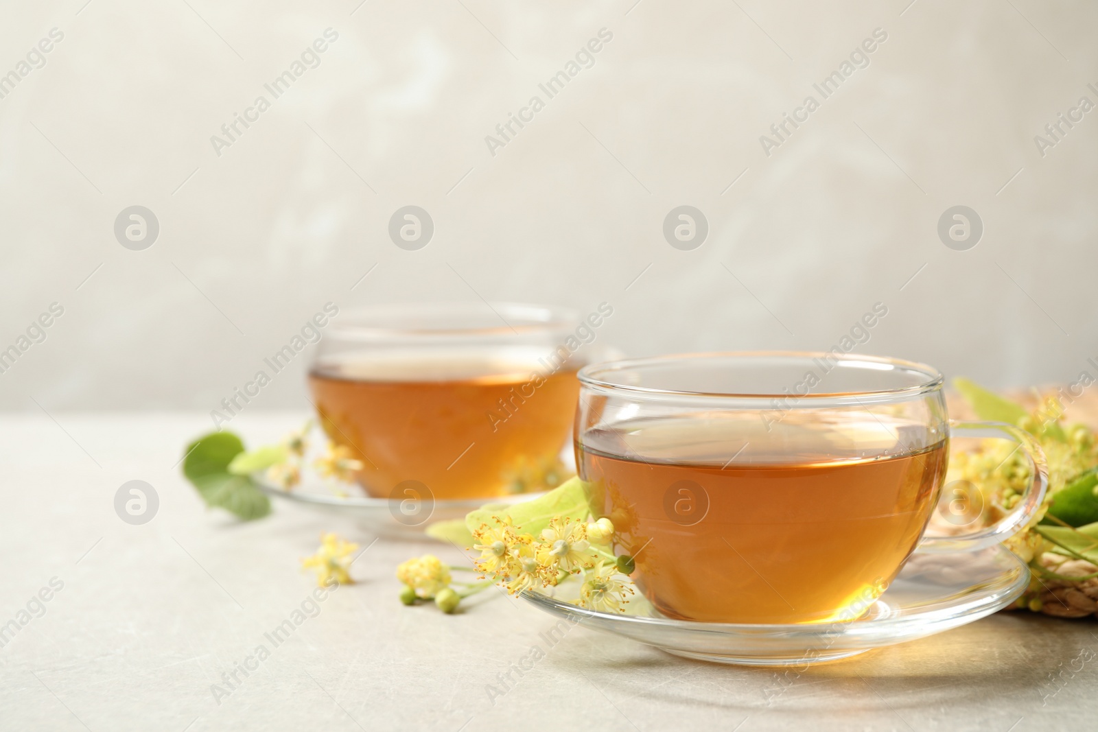 Photo of Tasty tea and linden blossom on light grey table. Space for text