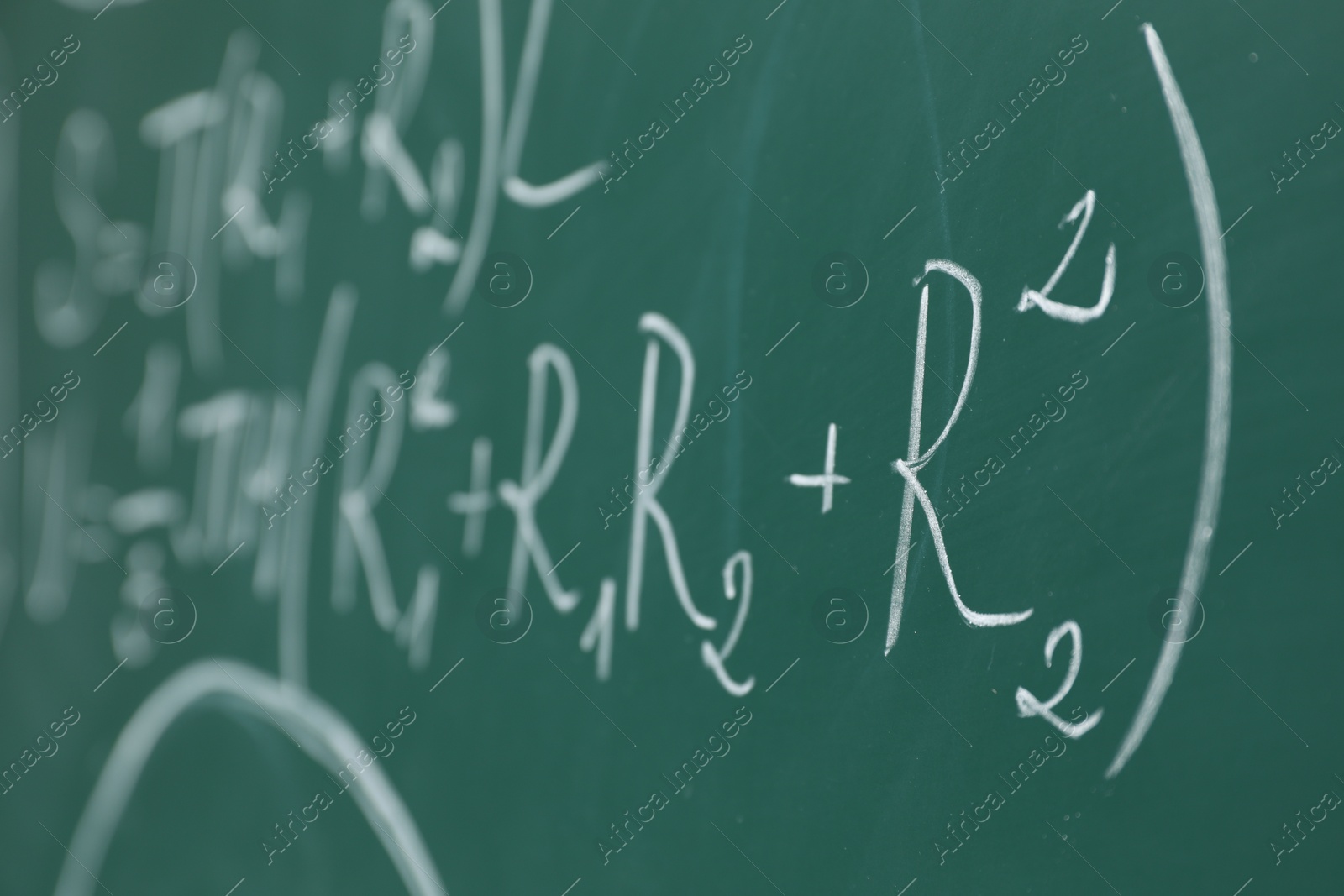 Photo of Different math formulas written with chalk on green board