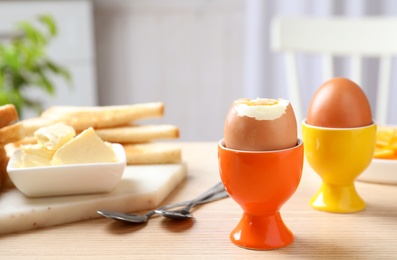 Cups with soft boiled eggs on wooden table, space for text. Healthy breakfast