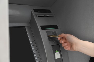 Photo of Woman inserting credit card into cash machine outdoors, closeup