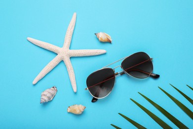 Photo of Stylish sunglasses, starfish and seashells on light blue background, flat lay