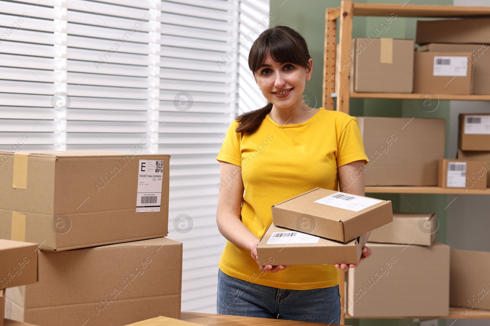 Photo of Parcel packing. Post office worker with parcels indoors