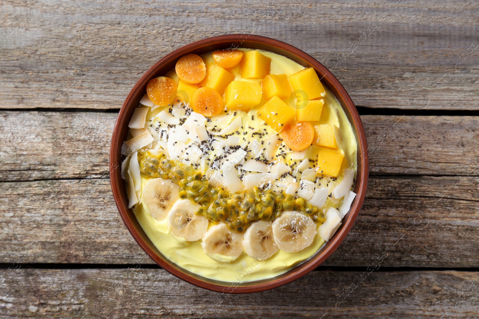 Photo of Tasty smoothie bowl with fresh fruits on wooden table, top view