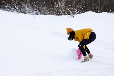 Photo of Woman making ball for snowman outdoors. Winter vacation