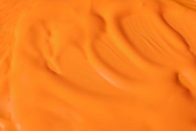 Photo of Bright orange paint as background, closeup view