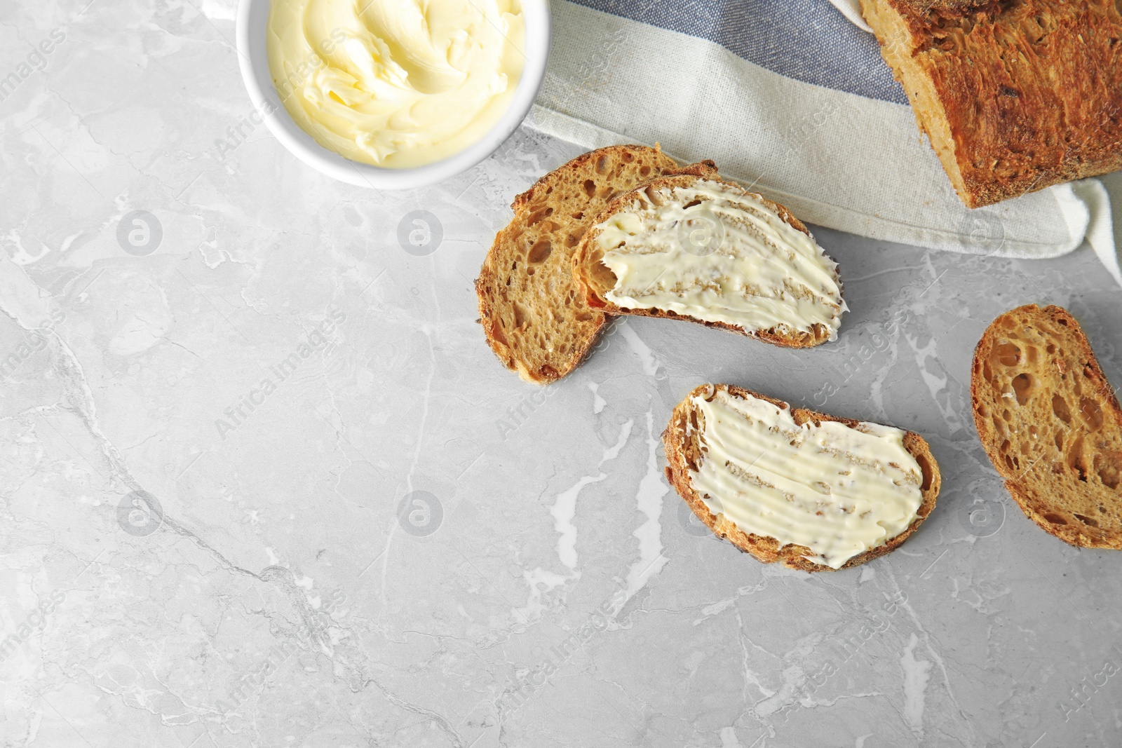 Photo of Tasty bread with butter served for breakfast on grey marble table, top view. Space for text