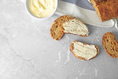 Photo of Tasty bread with butter served for breakfast on grey marble table, top view. Space for text