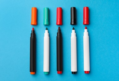 Photo of Bright color markers on light blue background, flat lay