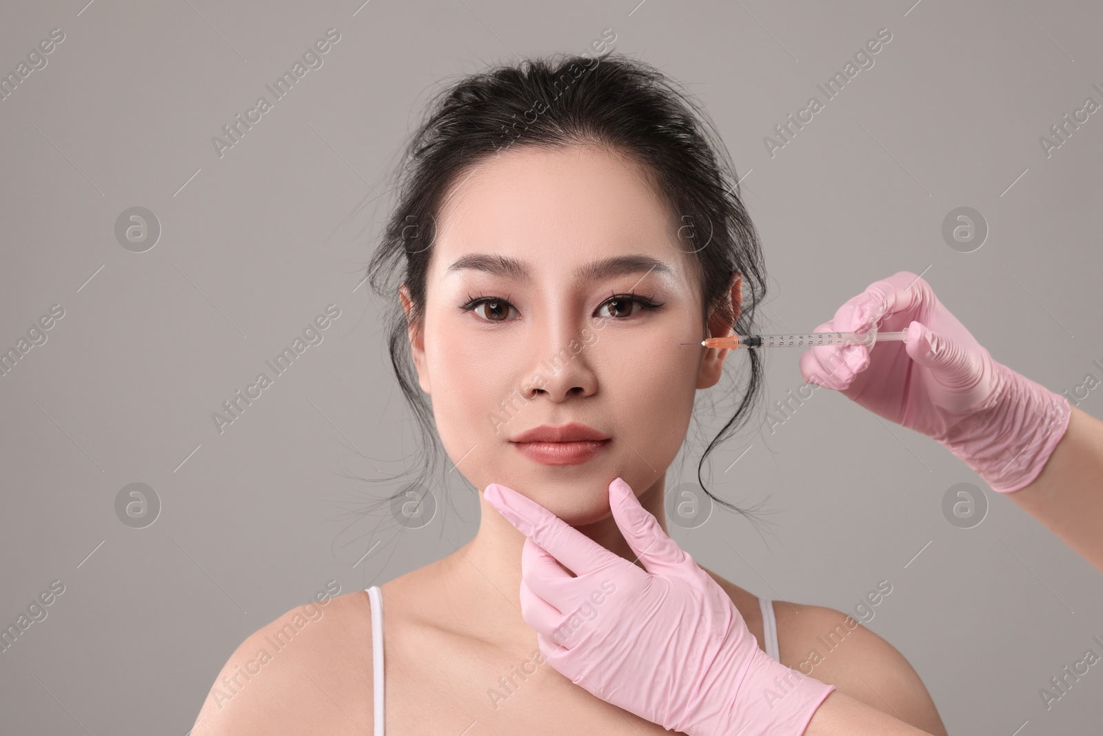 Photo of Woman getting facial injection on grey background