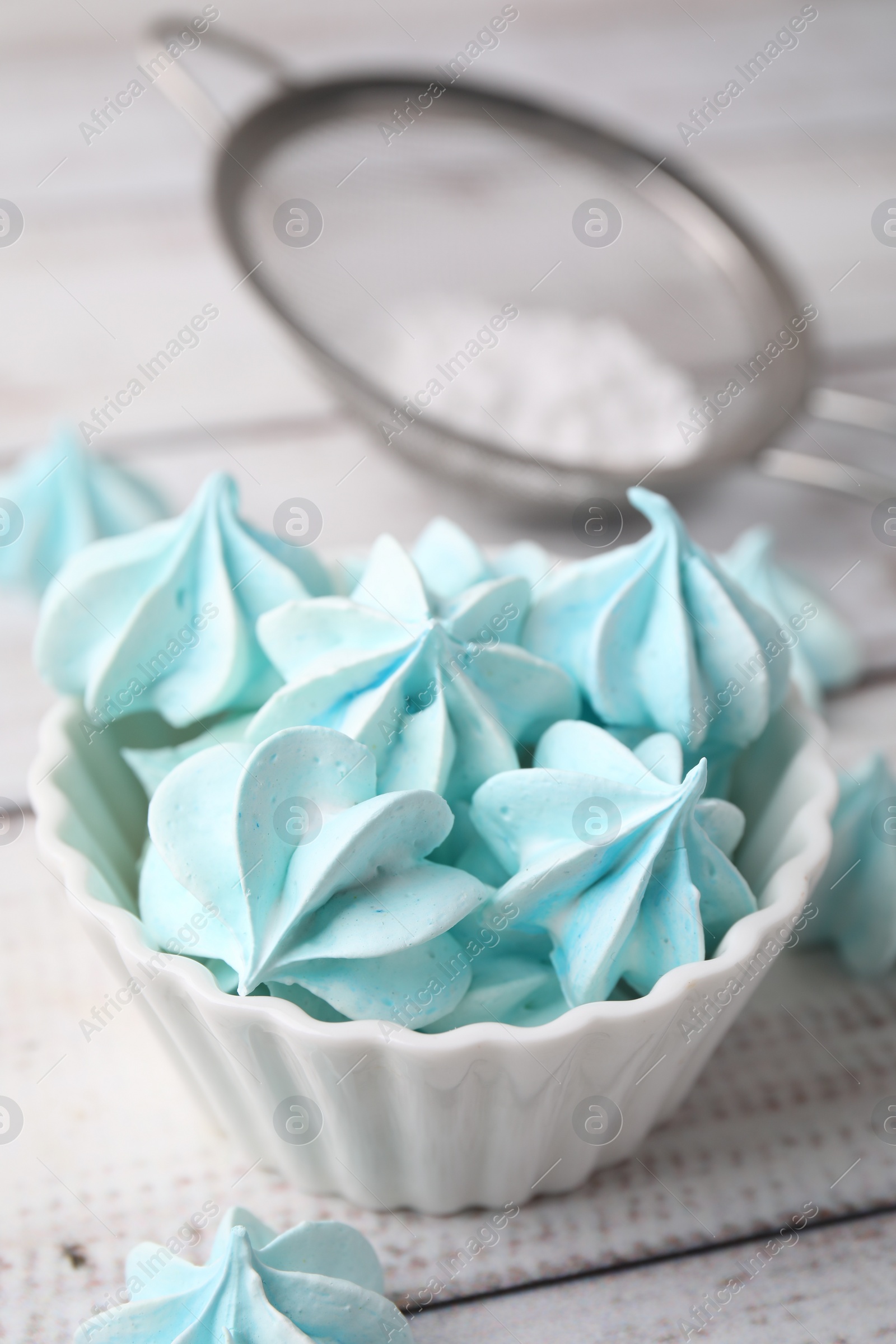 Photo of Tasty meringue cookies in bowl on white wooden table