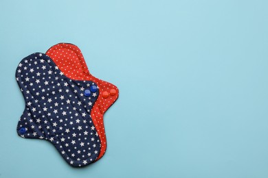 Photo of Reusable cloth menstrual pads on light blue background, flat lay. Space for text