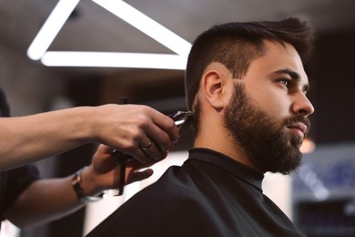 Photo of Professional hairdresser working with client in barbershop