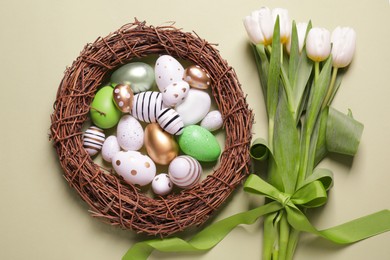 Photo of Flat lay composition of painted Easter eggs and tulip flowers on light green background