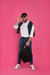 Young man with stylish backpack on pink background