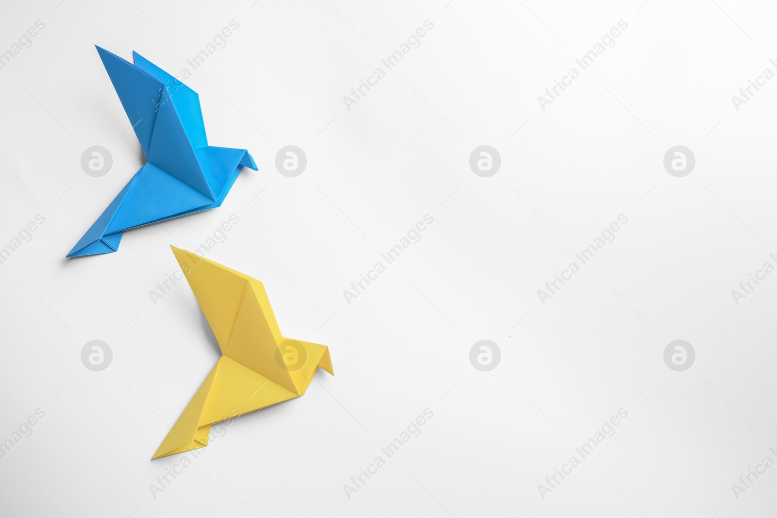 Photo of Beautiful colorful origami birds on white background, flat lay. Space for text
