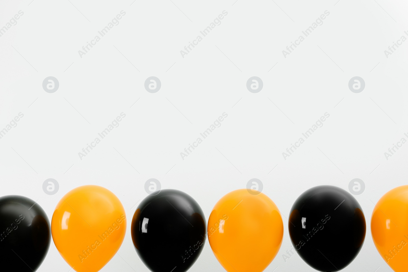 Photo of Colorful balloons on light background, space for text. Halloween party
