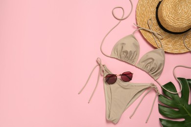 Stylish bikini, straw hat, sunglasses and tropical leaf on pink background, flat lay. Space for text