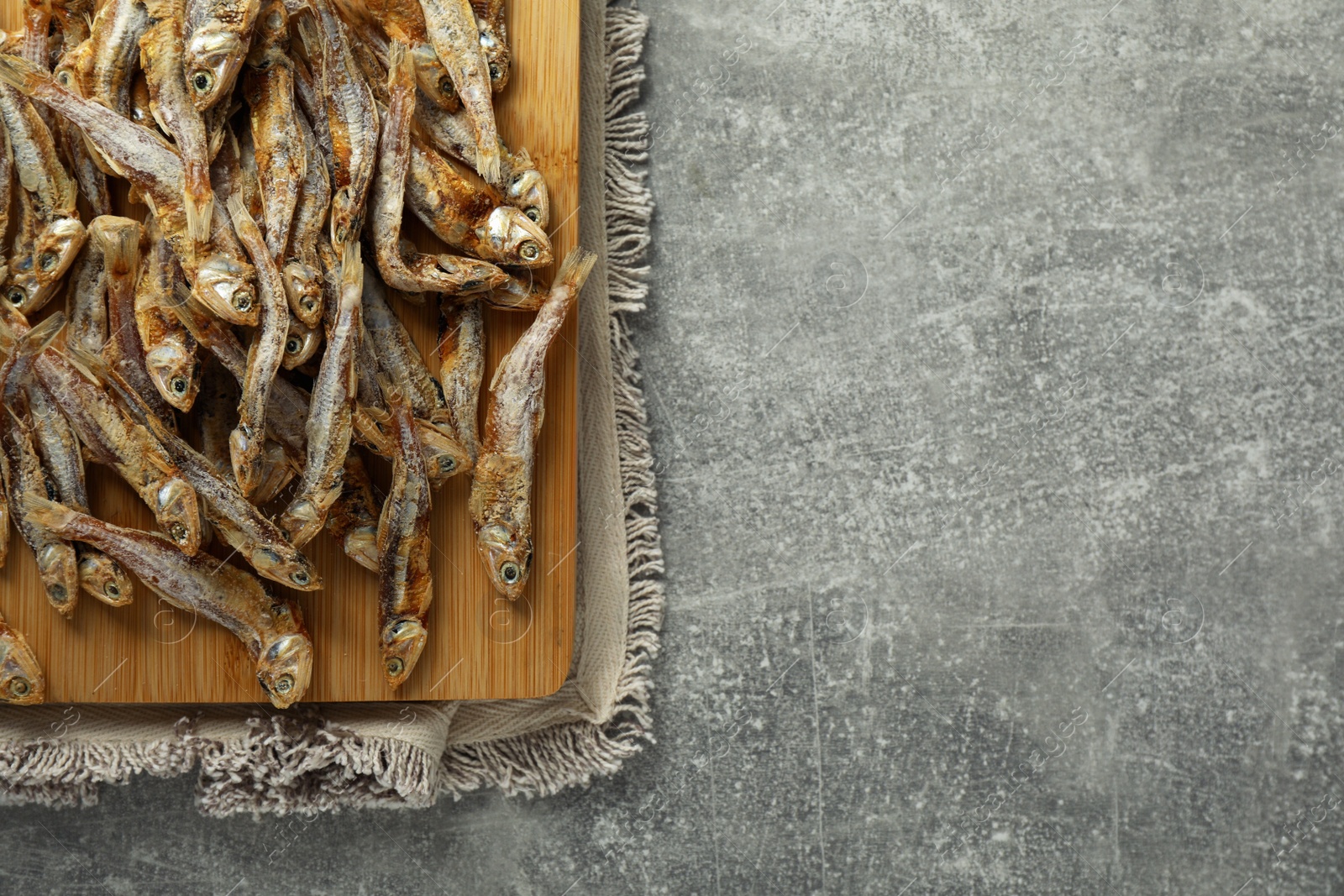 Photo of Delicious dried anchovies on grey table, top view. Space for text