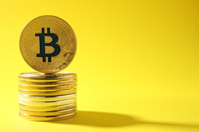 Stack of bitcoins on color background, space for text. Digital currency