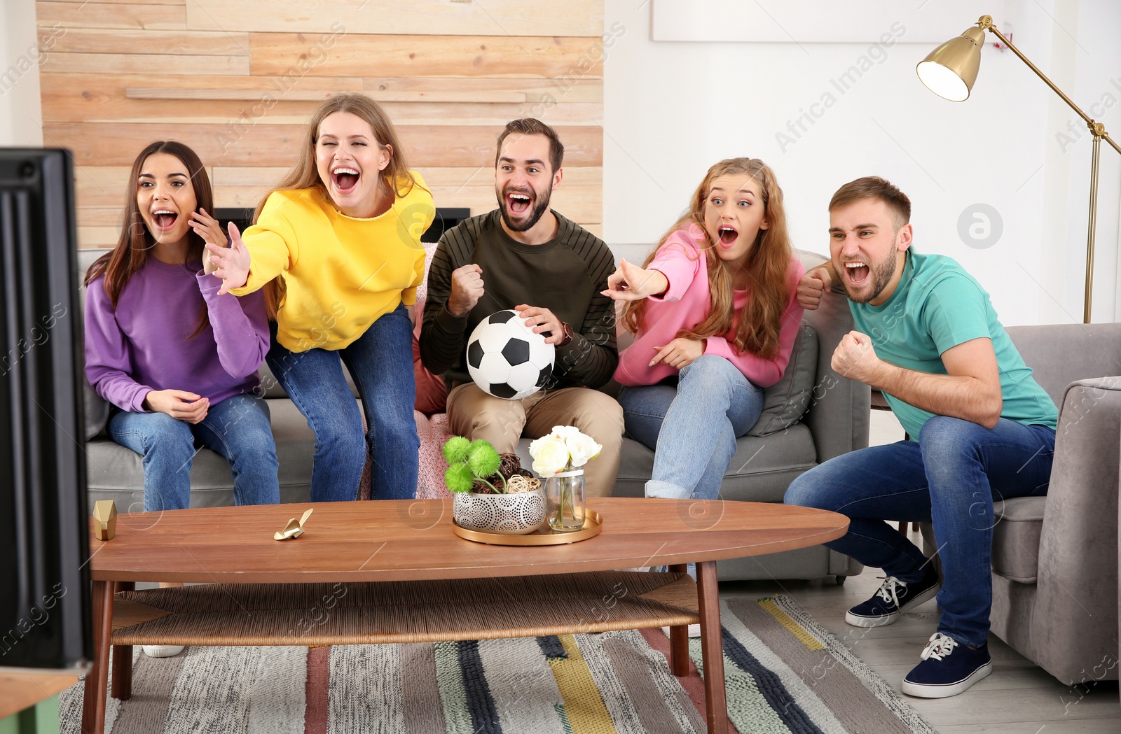Photo of Group of friends celebrating victory of favorite soccer team in living room