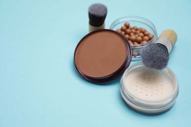 Photo of Different face powders and brushes on light blue background. Space for text