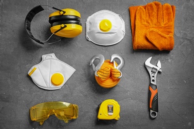 Photo of Flat lay composition with tools and safety equipment on grey background