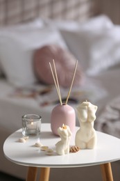 Beautiful body shaped candles, seashells and air reed freshener on table indoors